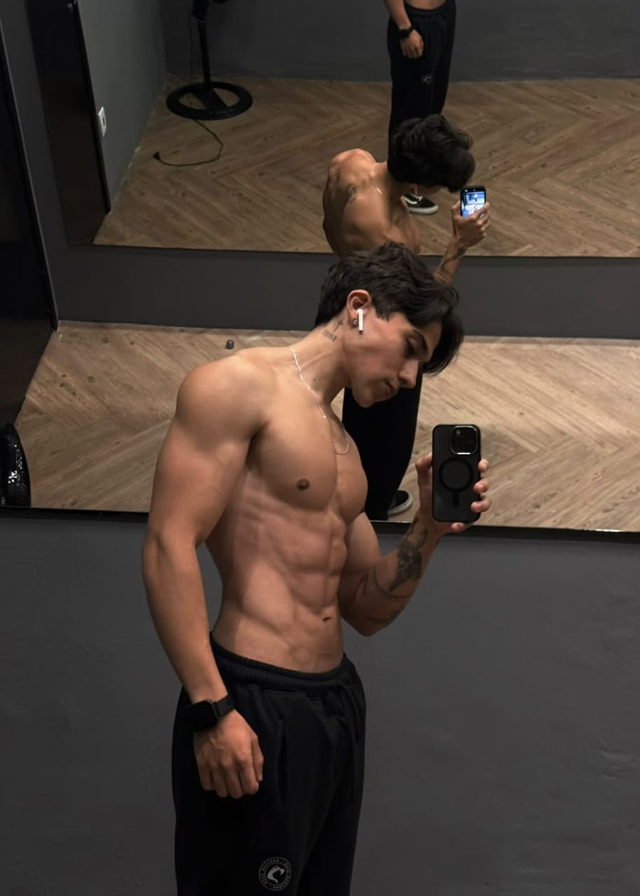 João Vitor, o Jota, sem camisa em frente ao espelho da academia